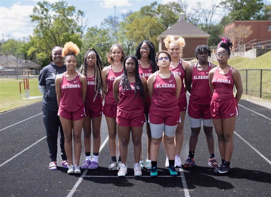  Nine track athletes and their coach look to the camera from the A.S.D. Track.